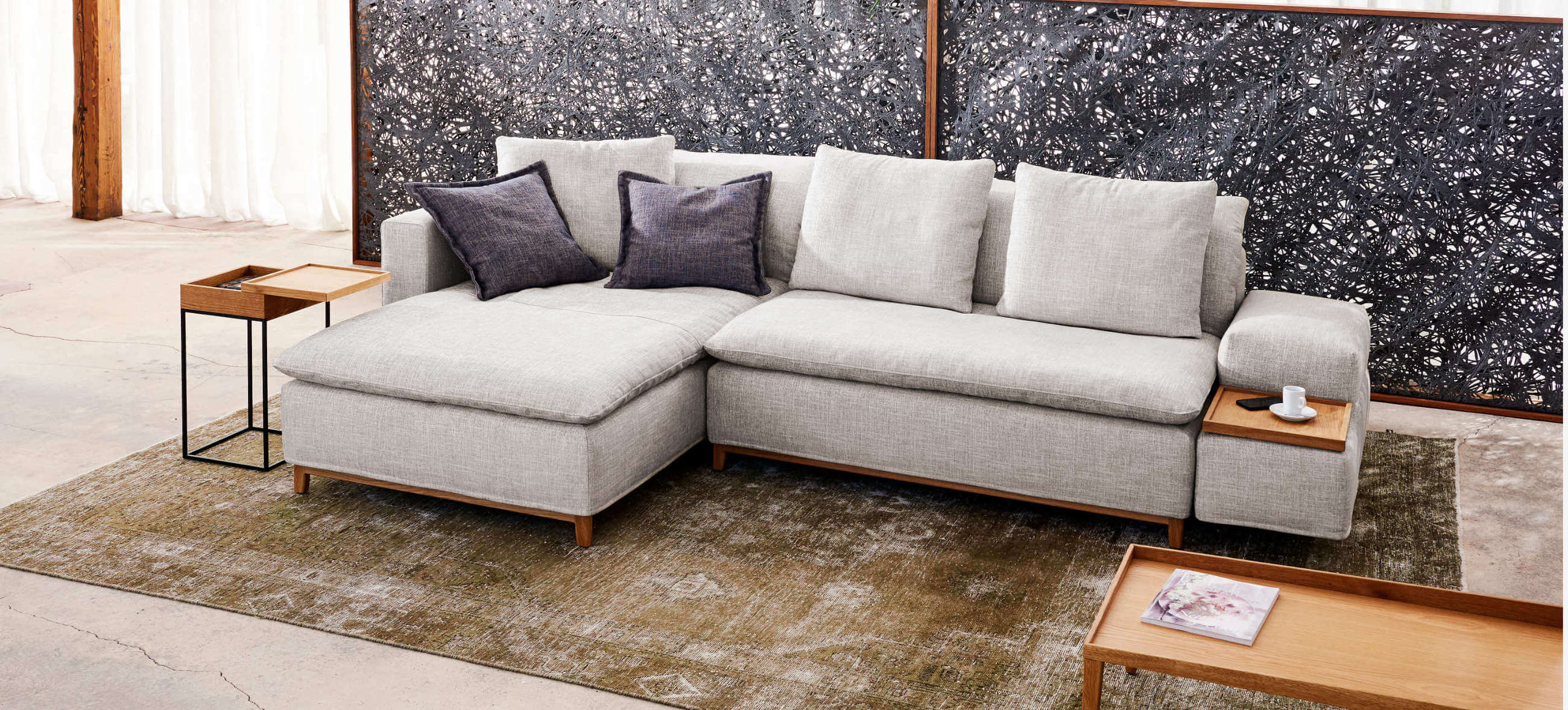 Kompaktes Ecksofa Isla von Signet in hellem Stoff mit Holzdetails und gemütlichen Kissen.