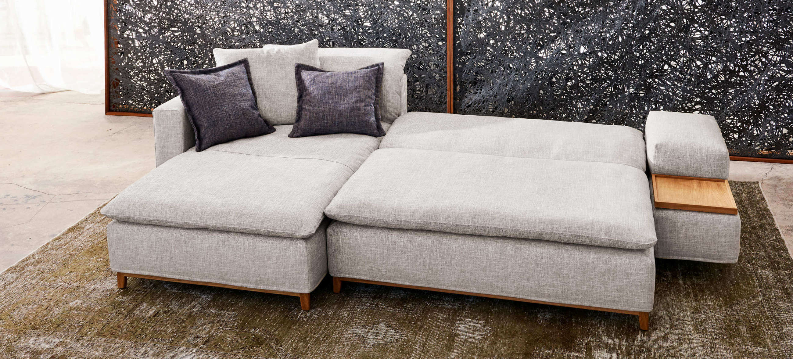 Isla Ecksofa von Signet, ausgeklappt als Schlafsofa mit großzügiger Liegefläche und integriertem Holzdetail.