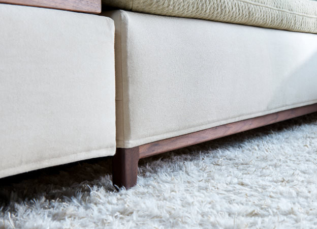 Detailansicht der Nussbaum-Holzkufen des Isla Sofas von Signet, warmes und modernes Design.