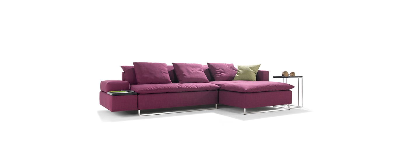 Ecksofa Isla von Signet in kräftigem Pink mit eleganten Edelstahlfüßen und Kissen.