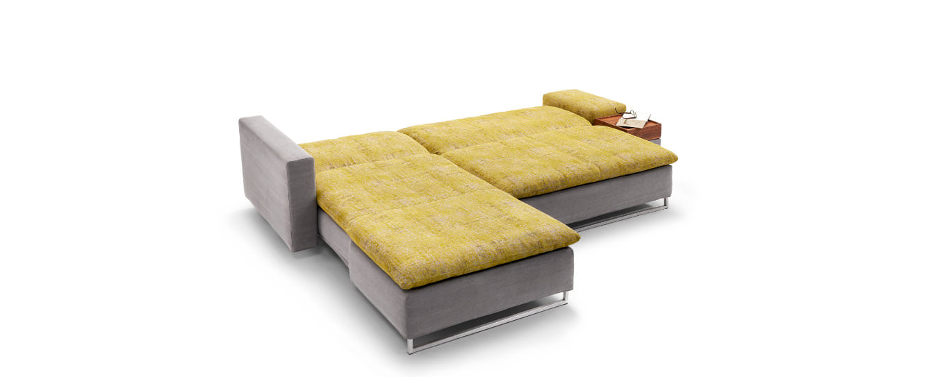 Ausgeklapptes Isla Ecksofa von Signet in grauem Korpus mit gelber Liegefläche und Edelstahlfüßen. 
